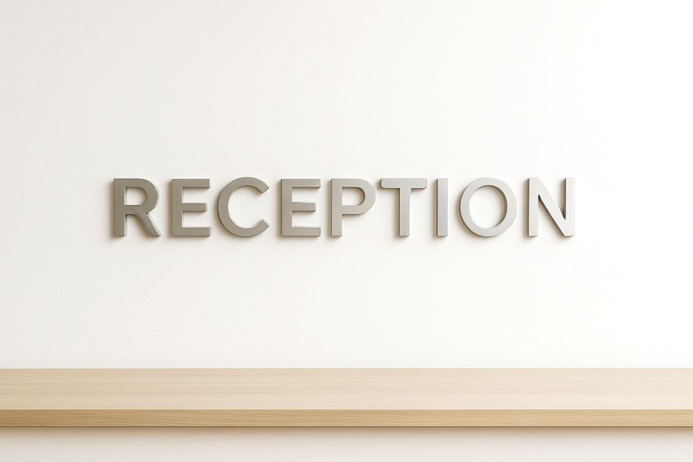 グレー壁にヘアライン仕上げのステンレス切り文字RECEPTIONを設置した写真